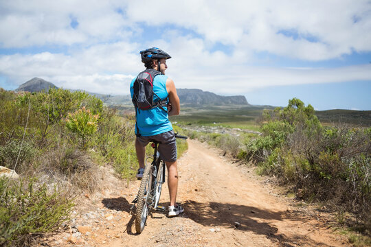 Fototapeta Mountain bike resting on dirt trail winding through rocky scrubland under flat-topped mountains