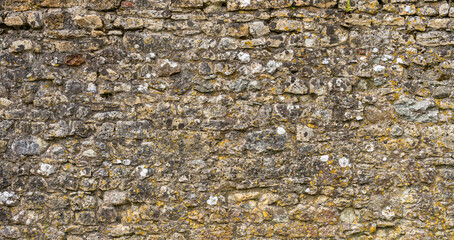Close-up of a weathered stonek wall in English medieval castle worn and eroded with age to make perfect background