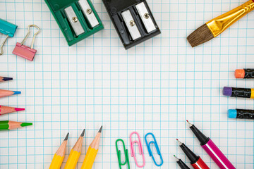 Flat lay of colorful school supplies on graph paper with copy space.