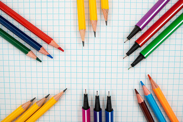 Back to school flat lay with colorful pencils and pens on graph paper with copy space.