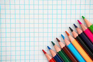 Back to school flat lay with colorful pencils on graph paper with copy space.