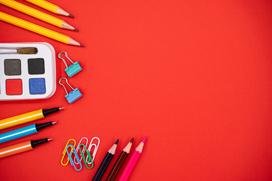 Back to school flat lay with colorful stationery on red background with copy space.
