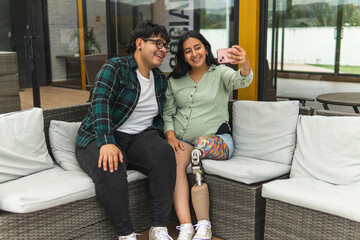 Happy latin american couple taking selfie outdoors with prosthetic leg