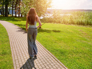 Young woman with slim body type is walking in well maintained and clean city park on a warm sunny...
