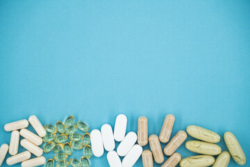 Various dietary supplements and pills on blue background with copy space.