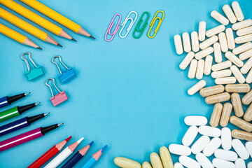 Back to school essentials and dietary supplements on blue background with copy space.