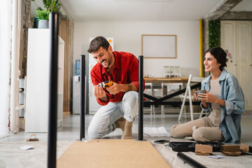 Couple assembling furniture while consulting instructions on smart phone