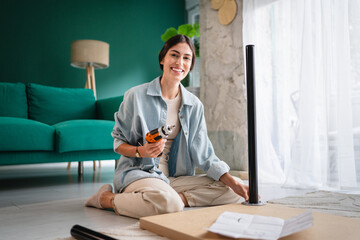 Woman assembling furniture using cordless screwdriver at home