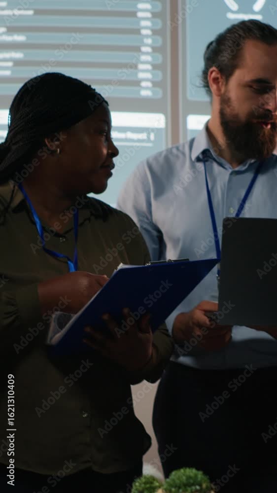 Poster vertical video portrait of multiethnic business team collaborating late at night, assembling in a da