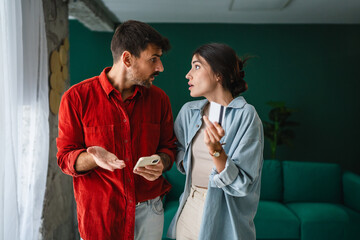 Young couple arguing about credit card and smart phone at home