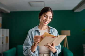 Young adult caucasian woman smiling and reading a book at home