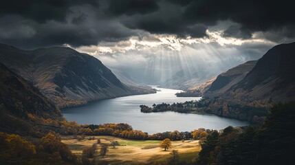 Stunning view of a valley with a lake and mountains under dramatic clouds and sunlight shining through. Nature at its best.