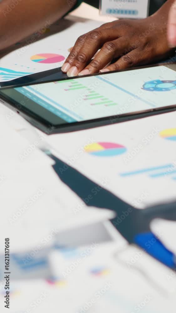 Poster Vertical Video Diverse team members meeting after hours to share data reports, discuss business intel and prepare forecasts for upcoming presentations to enterprise shareholders after hours. Camera B.