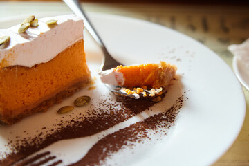 Delicious slice of pumpkin cheesecake topped with whipped cream and pumpkin seeds, served on a...