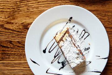 Delicious slice of cake topped with powdered sugar and chocolate drizzle, elegantly presented on a...