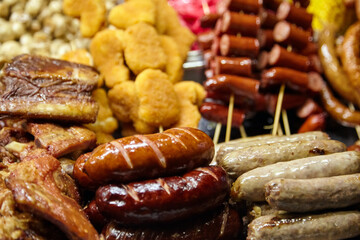 Assorted grilled meats including sausages, chicken nuggets, and skewered hot dogs displayed on a market table, showcasing vibrant colors and appetizing textures for culinary enthusiasts