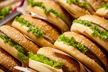 Freshly prepared sesame seed buns filled with crisp lettuce, stacked neatly in a display,...