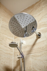Modern showerhead with sleek chrome finish is mounted on tiled wall, showcasing water flow and...
