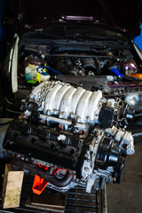 Engine swap in action featuring intake and transmission. Engine Swap in Progress. Custom V8 engine prepared for installation in drift car. Highlighting headers, intake, and pulley system.