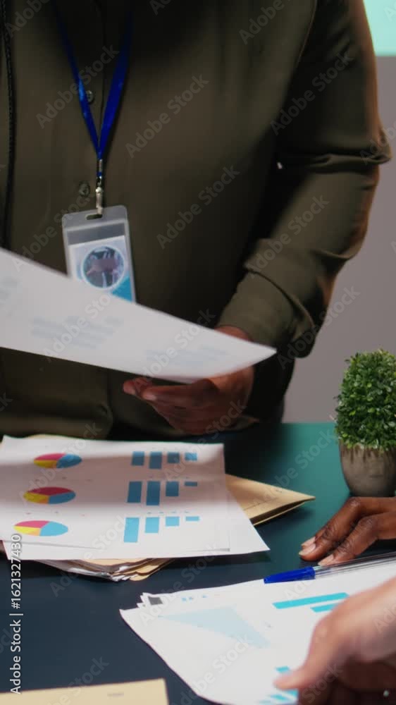 Poster vertical video diverse team members meeting after hours to share data reports, discuss business inte