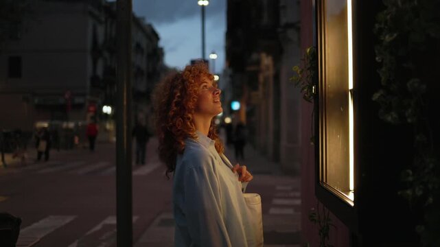Curious woman observing illuminated shop window in slow motion
