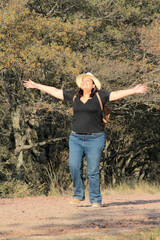 A 40-year-old Latina woman hikes in the mountains to fully enjoy nature and sunlight, experiencing well-being and empowerment