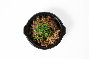 Buckwheat porridge with stewed beef and vegetables, served on a plate and garnished with fresh herbs