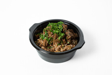 Buckwheat porridge with stewed beef and vegetables, served on a plate and garnished with fresh herbs
