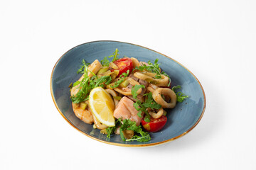 Seafood salad with arugula, cherry tomatoes, lemon, and pieces of fish and squid, served on a plate
