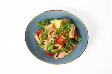 Seafood salad with arugula, cherry tomatoes, lemon, and pieces of fish and squid, served on a plate