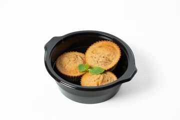 Homemade banana muffins with fresh banana slices and mint leaves, served on a plate. Isolated on white background