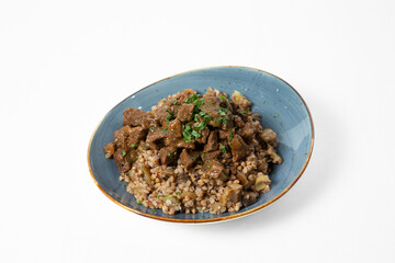Buckwheat porridge with stewed beef and vegetables, served on a plate and garnished with fresh herbs