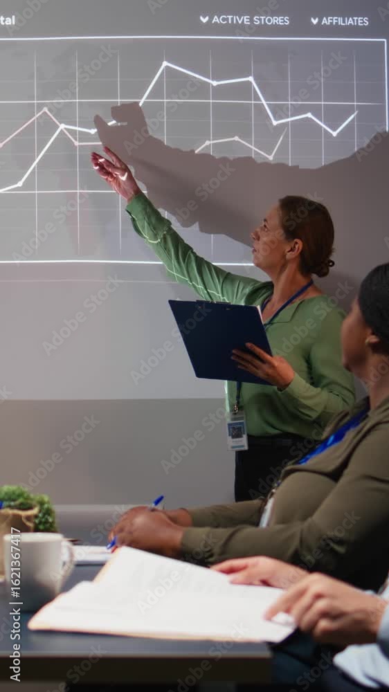Poster vertical video diverse business associates reviewing performance metrics data within the multination