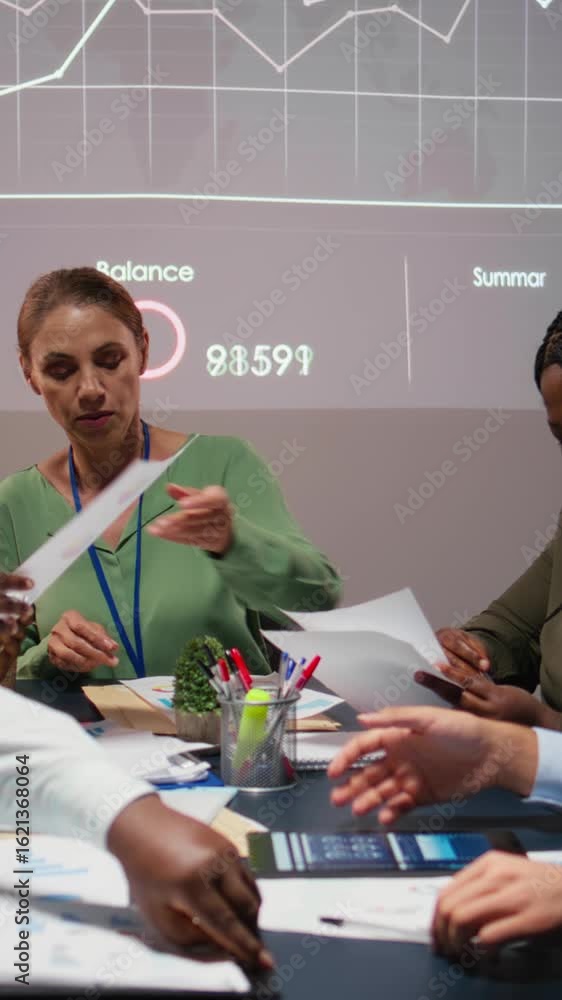 Poster vertical video close up of diverse business team meeting after hours for visual data reports, review