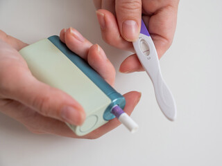 Woman holding pregnancy test and e-cigarette. 