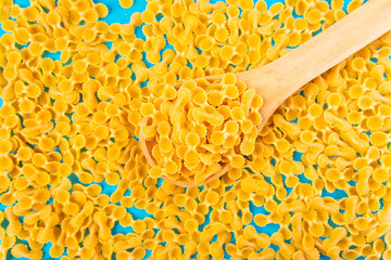 Noodles in a wooden spoon on a blue surface and a chopping board with happy and sad expressions