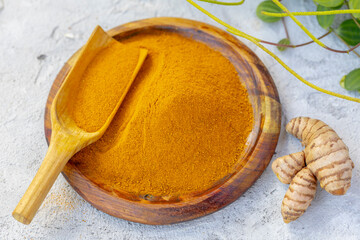 Fresh and ground turmeric root on a slate background