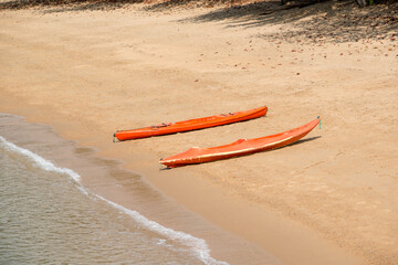 Two brightly colored kayaks rest on the golden sands of Palm Cove, Queensland, facing the calm...