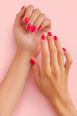 Womans hands with trendy manicure on pastel pink background. Beauty salon concept.