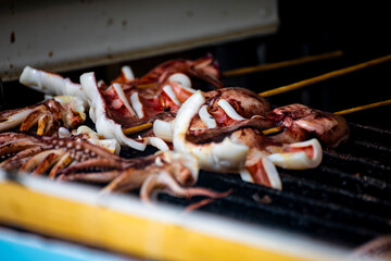 the process of squid being grilled or cooked on a hot plate. Large squid are placed on a heat source