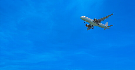 Naklejka premium White passenger airplane flying in a deep blue sky