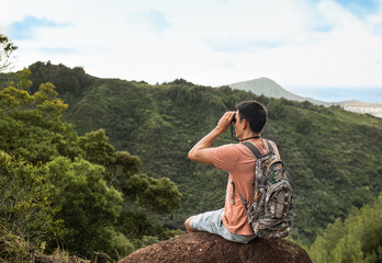 Naklejka premium Young man hiker stoping to enjoy the beautiful Hawaii mountain views 