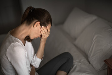 Depressed tired woman sitting in bed at home 