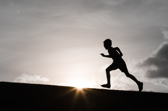 fit active healthy child running up a hill silhouette, sport fitness concept 