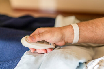 Close-up of a patient's hand calling for nurse with remote control in hospital bed