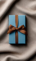 Light Blue Present Tied With a Brown Ribbon Rests on Soft Beige Fabric