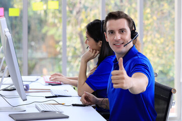  Focused male employee works on computer in corporate office answers client questions. Online...
