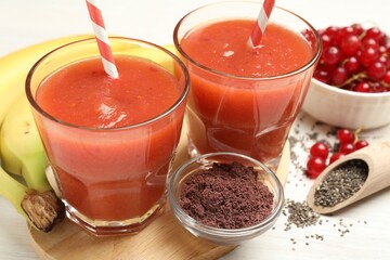 Superfood. Tasty smoothies in glasses and ingredients on light wooden table, closeup