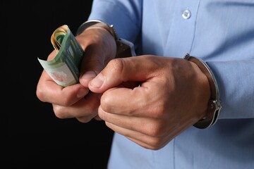 Corruption. Man in handcuffs holding euro banknotes on black background, closeup
