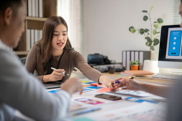A woman is sitting at a desk with a man and another woman